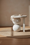 Table d'appoint sculpturale en résine finition travertin blanc avec base en sphères empilées pour salon